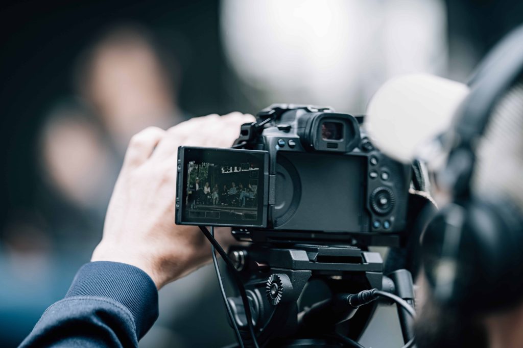 A professional cinematographer from Tone Production, a top Lafayette Video Production Company, filming a corporate interview in a modern office setting in Lafayette, LA.