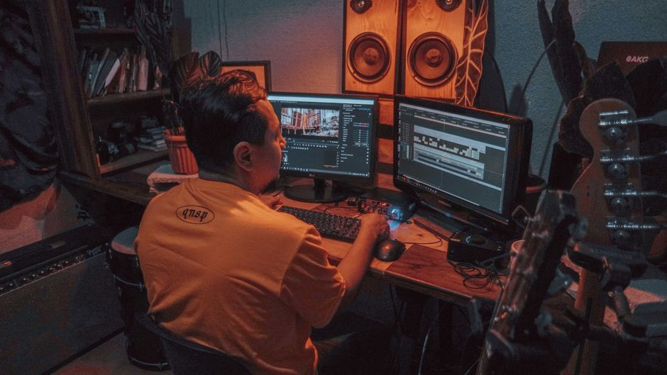Video editor selecting music licensing for video production on a laptop in a post-production studio
