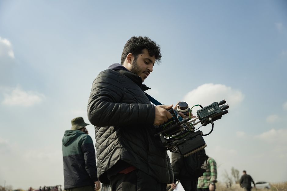 Videographer dialing in camera settings for video on a mirrorless camera in a professional production environment