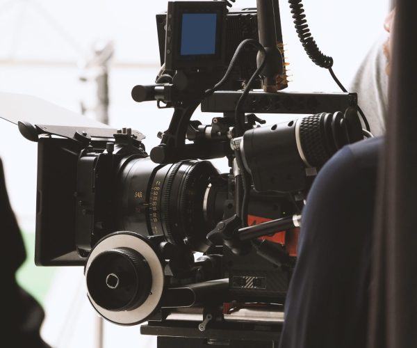 Behind the shooting or filming video movie and film production crew team setting up camera on tripod and professional equipment in studio for offline tv commercial or online web film recording.