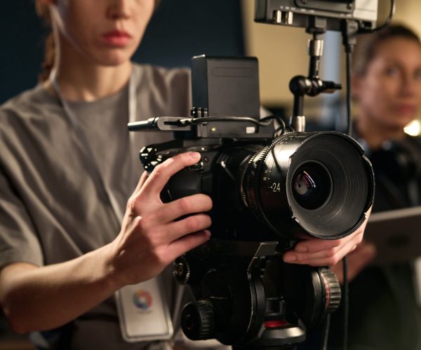 Close up of female hands holding professional video camera and operating equipment on set copy space
