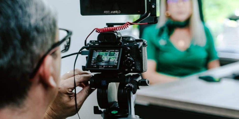 Cinematographer setting up lights and camera to film a professional interview at the office
