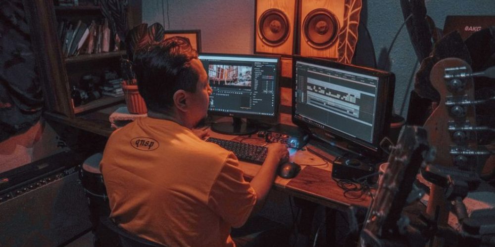Video editor selecting music licensing for video production on a laptop in a post-production studio