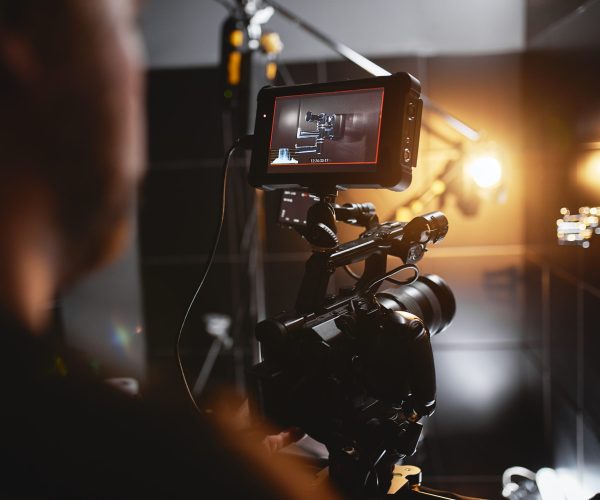 Video production backstage. Behind the scenes of creating video content, a professional team of cameramen with a director filming commercial ads. Video content creation, video creation industry, Low key, selective focus, film graine.