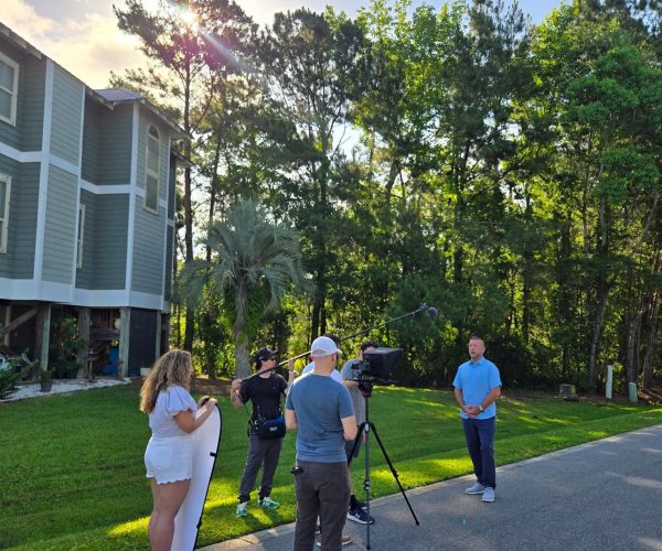 Tampa Bay business owner reviewing a video production company evaluation checklist with Benjamin Tone of Tone Production — five commercially objective criteria including commercial brief process, crew architecture, 8K RAW cinema technical ceiling, DaVinci Resolve post-production, and AI-generated semantic delivery laid out on a production planning document at a Tampa Bay brand video agency selection meeting