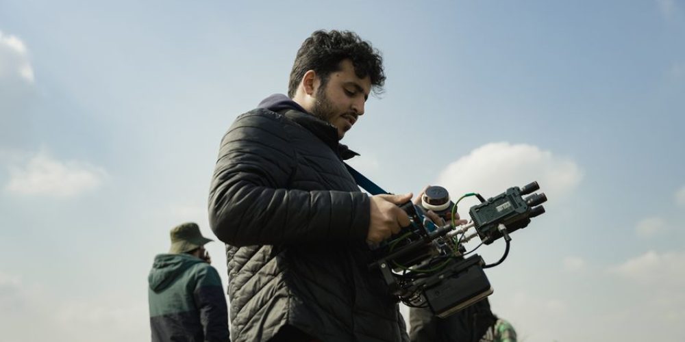 Videographer dialing in camera settings for video on a mirrorless camera in a professional production environment